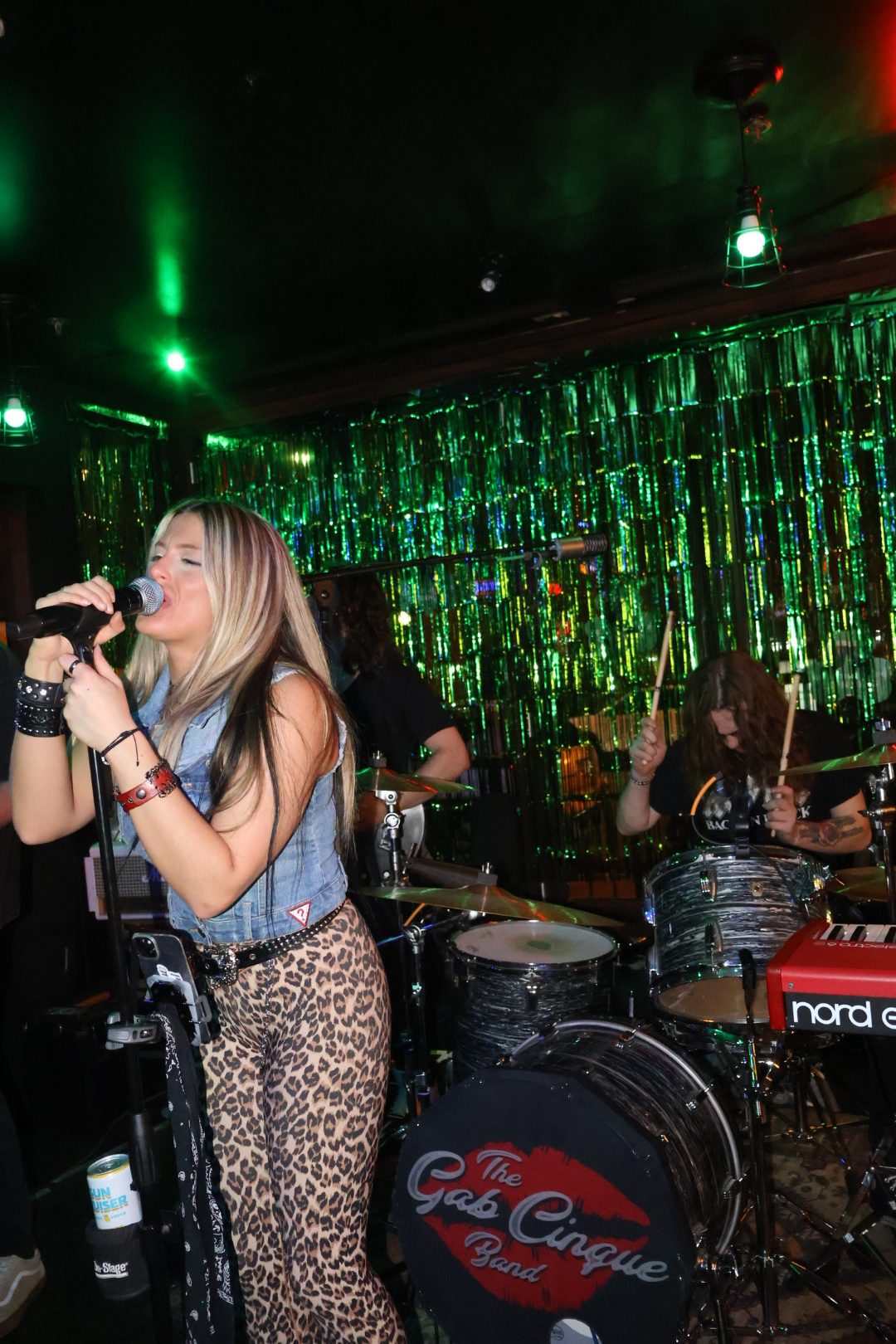 Drummer performing under green stage lights