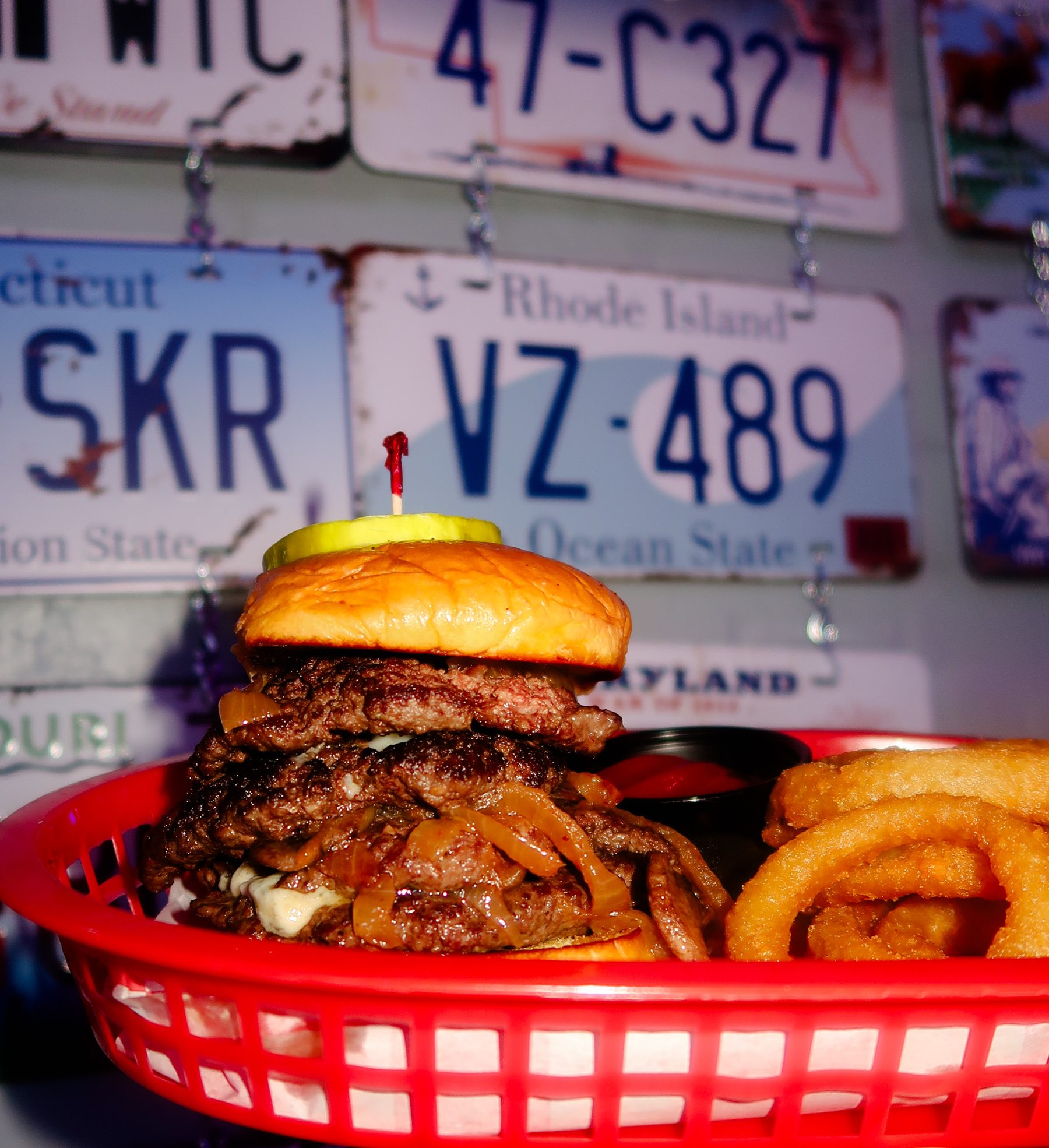 A River Street Garage smashburger stacked high, license plates on the wall behind it